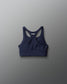 Navy blue sports bra with 'RUDIS' branding on a gray background