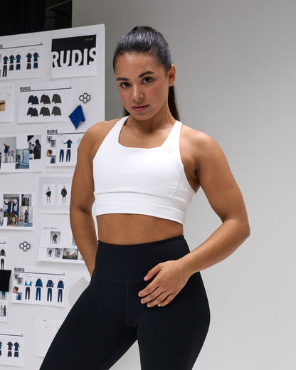 Woman in athletic wear standing in front of a RUDIS branded wall.