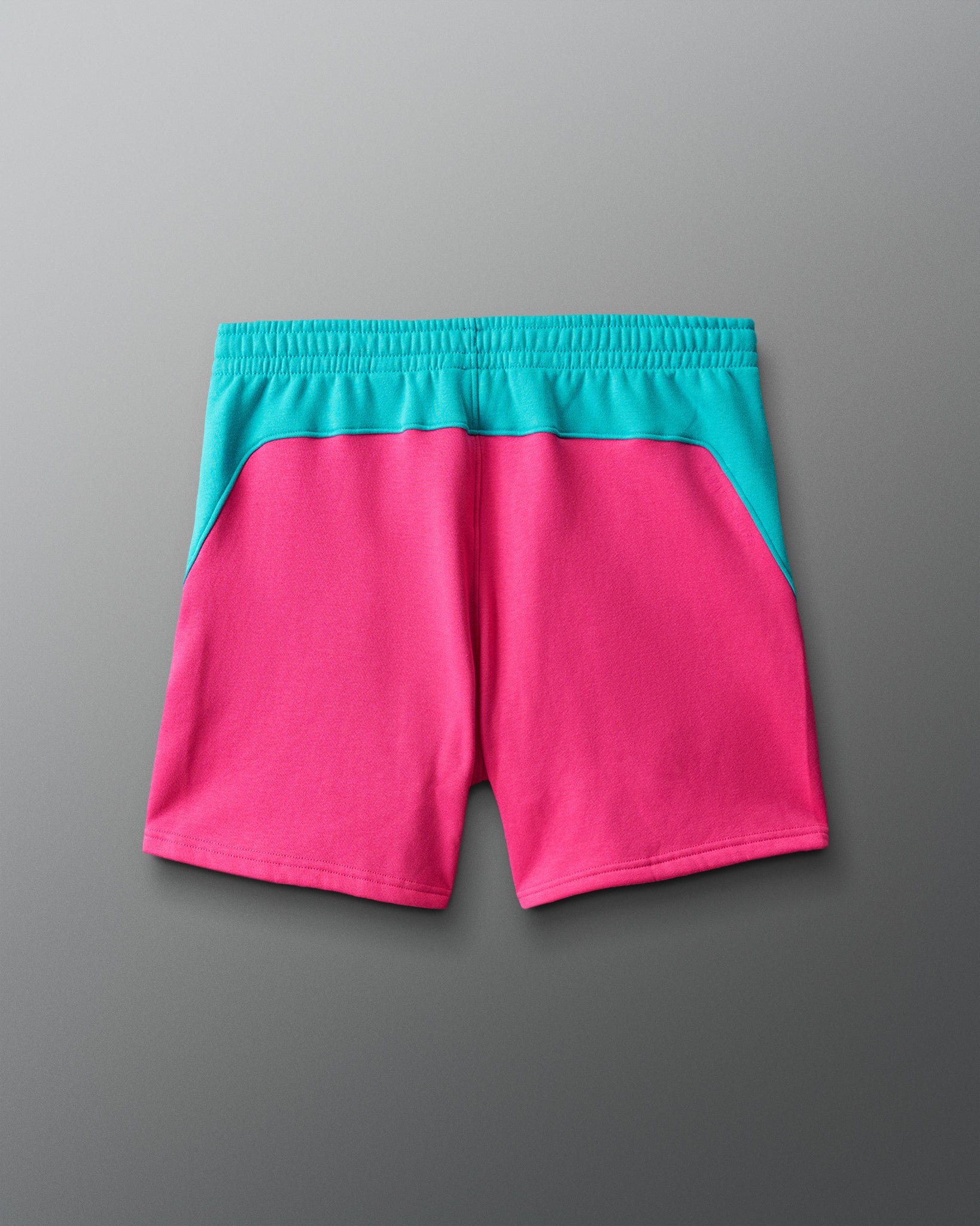 Pink shorts with teal waistband on a gray background
