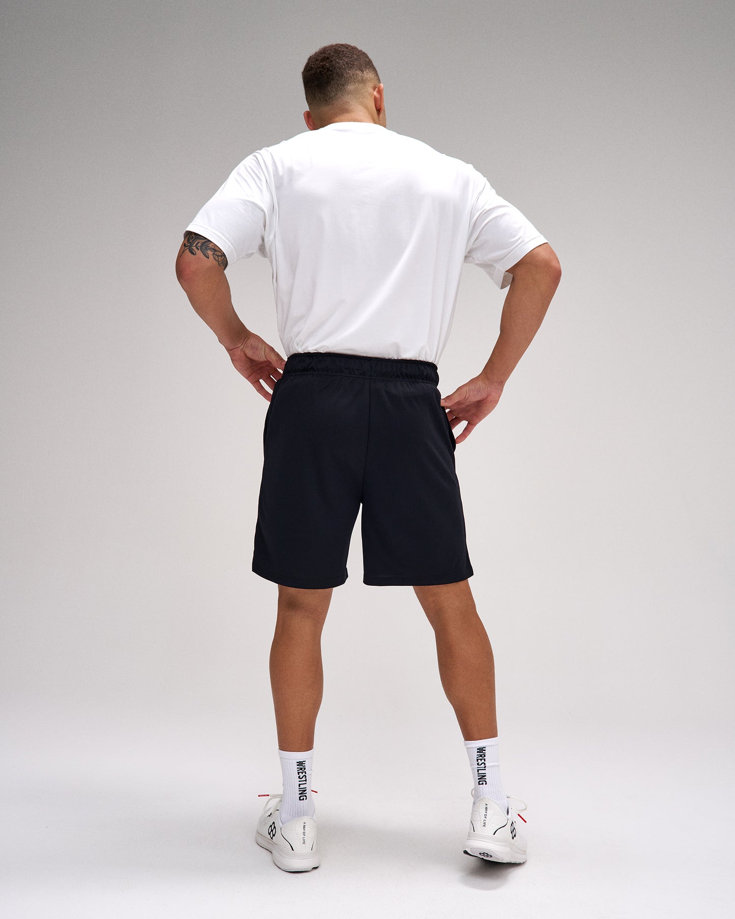 Person wearing a white t-shirt and black shorts on a gray background