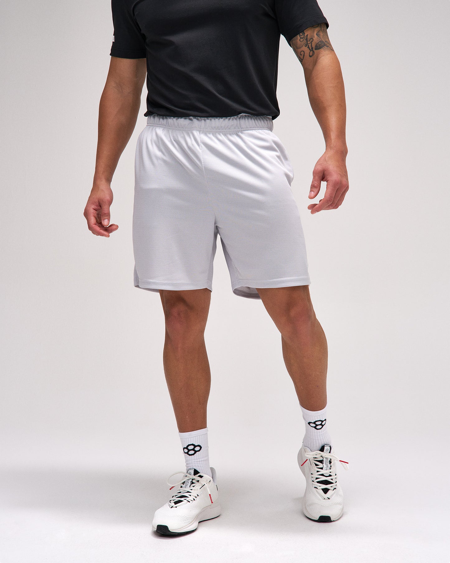 Person wearing white athletic shorts on a plain background