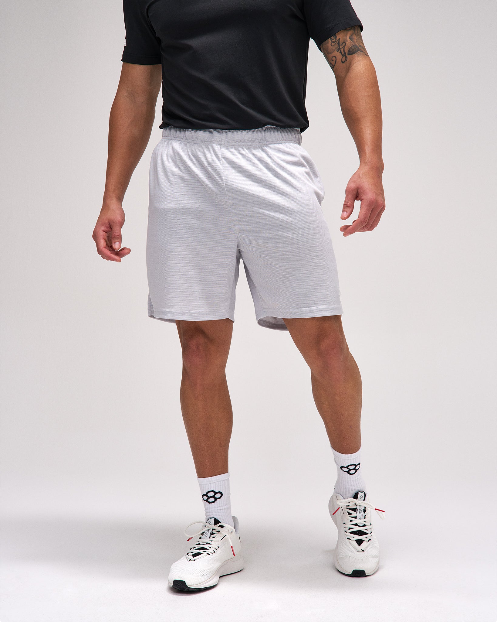Person wearing white athletic shorts on a plain background