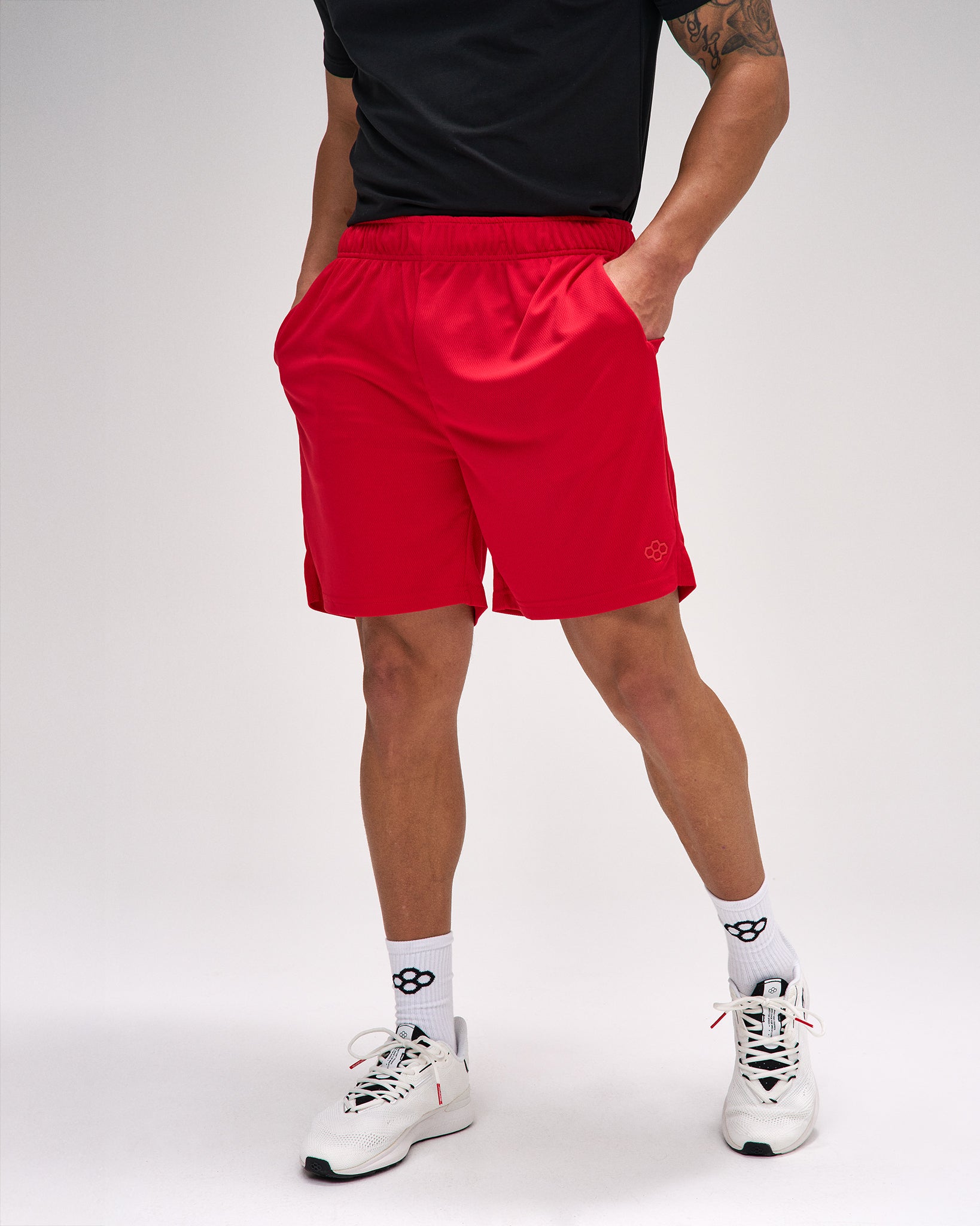 Person wearing red shorts and white sneakers on a plain background