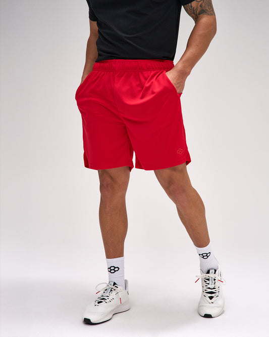 Person wearing red shorts and white sneakers on a plain background
