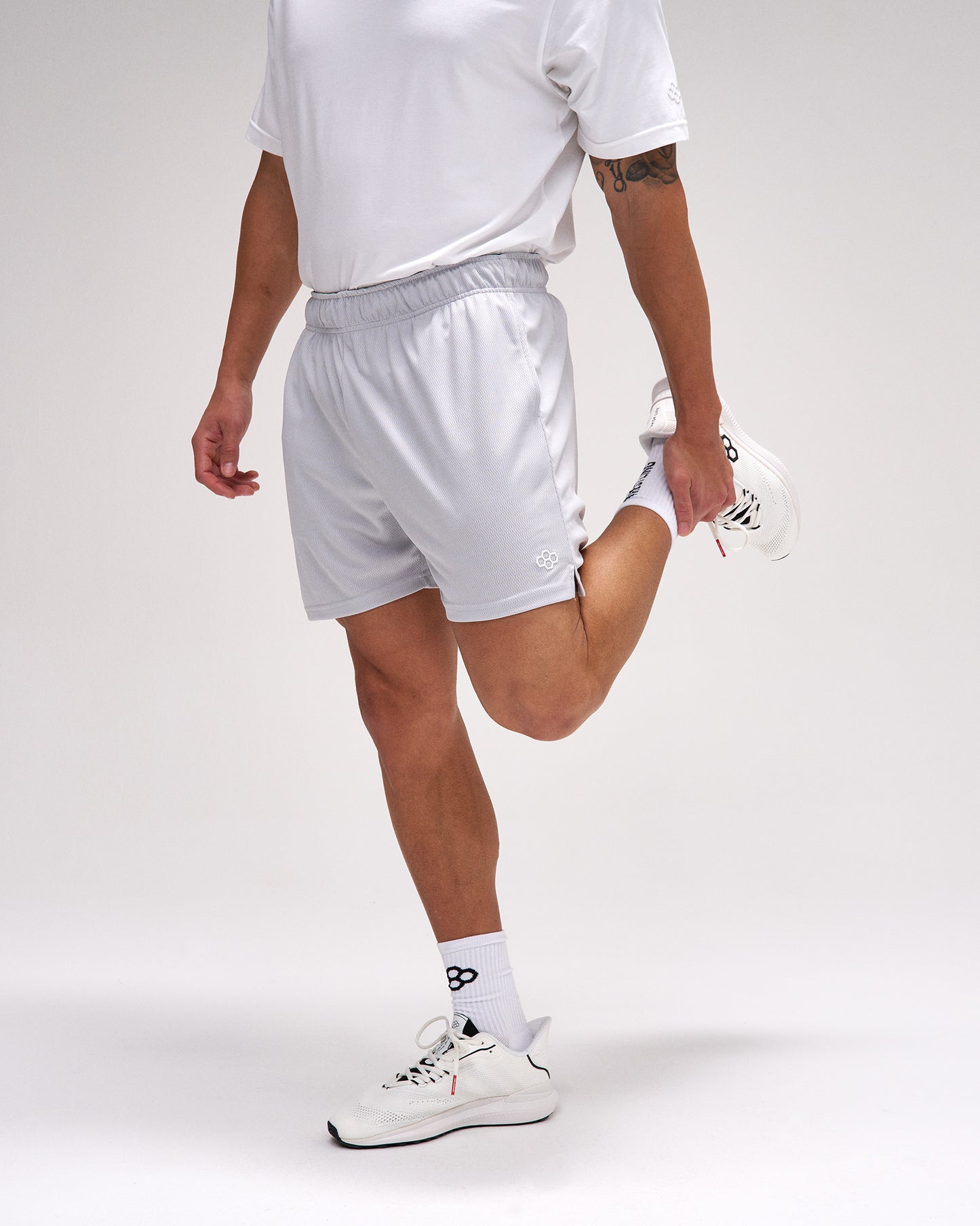 Person wearing white athletic shorts and shoes on a plain background