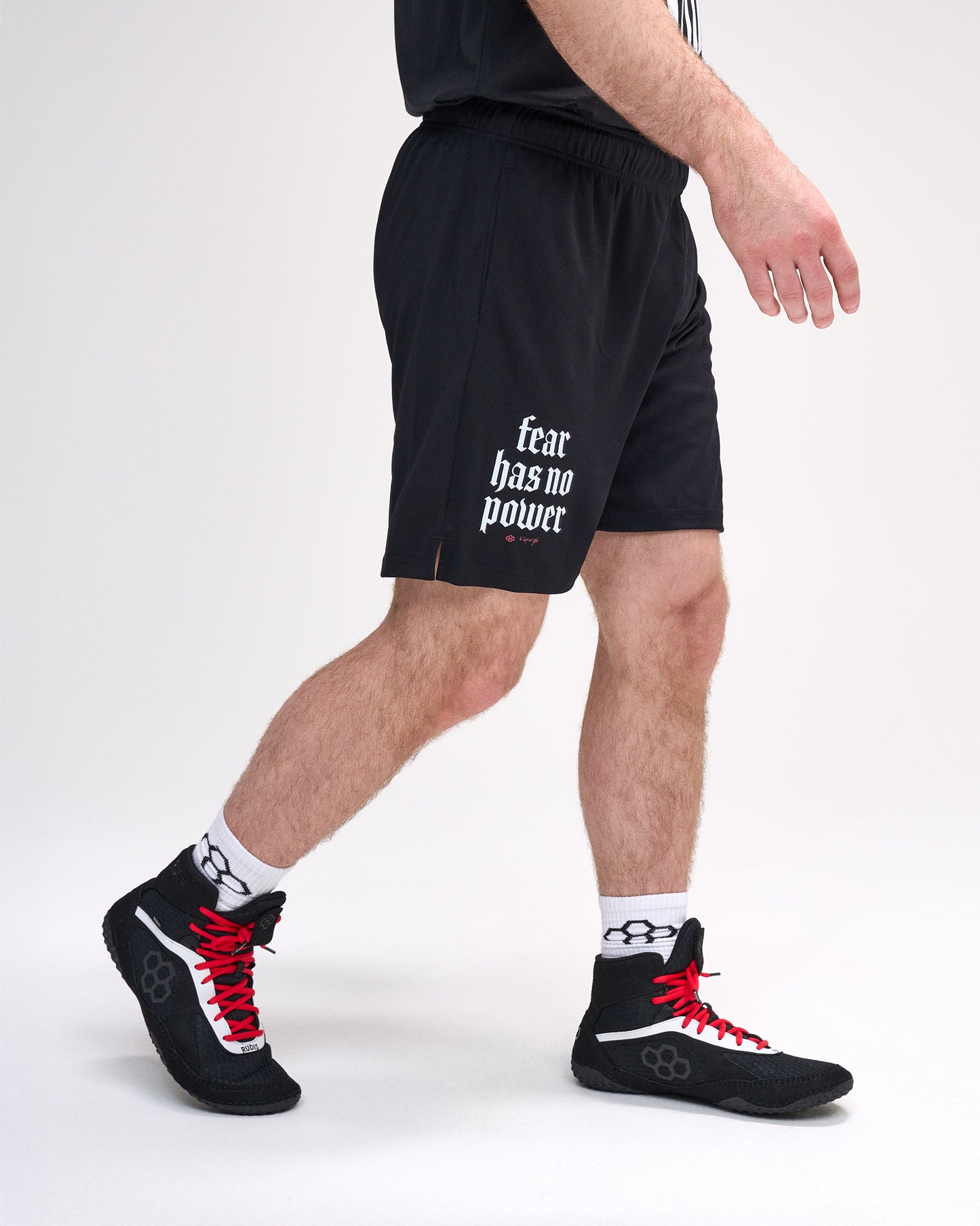 Person wearing black shorts with 'fear has no power' text and black sneakers on a white background