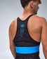Rear view of a man wearing a black wrestling singlet with a bright blue horizontal band and blue printed logo and text on the back, against a light gray studio background.