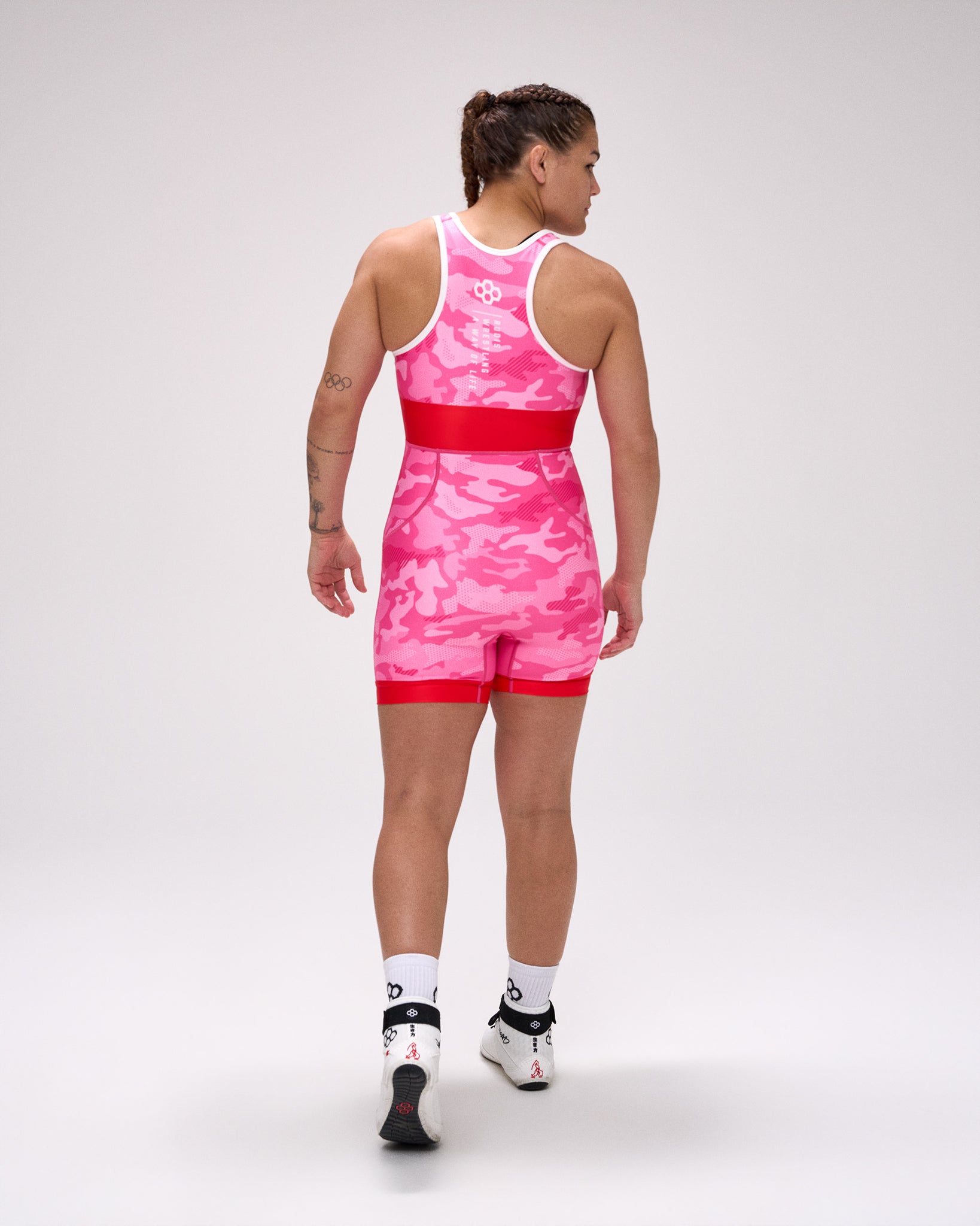Person wearing a pink and red wrestling singlet on a white background