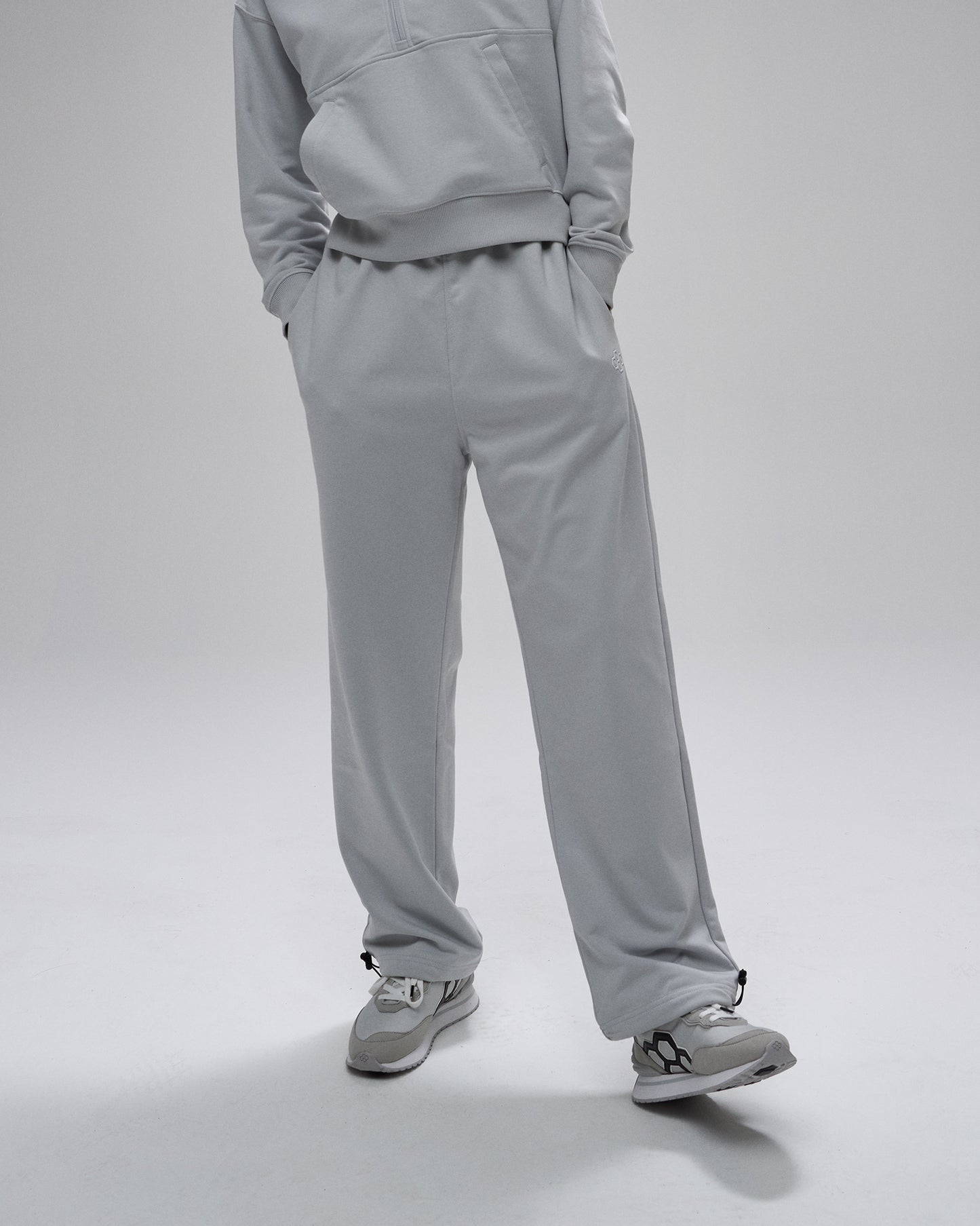 Person wearing a gray tracksuit on a light gray background