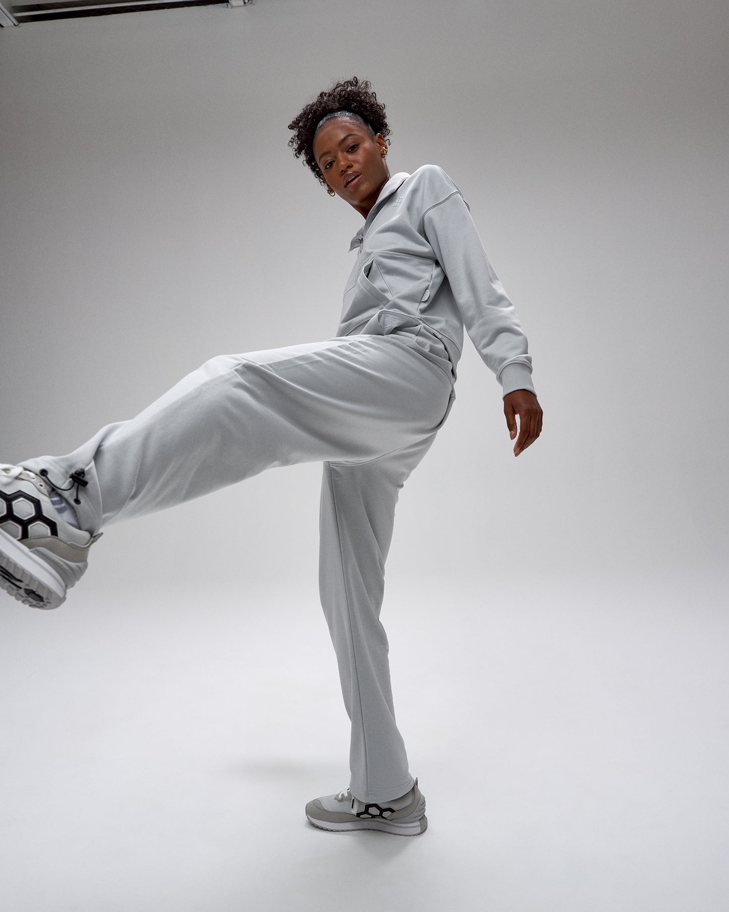 Person wearing a light gray tracksuit on a white background