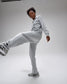 Person wearing a light gray tracksuit on a white background