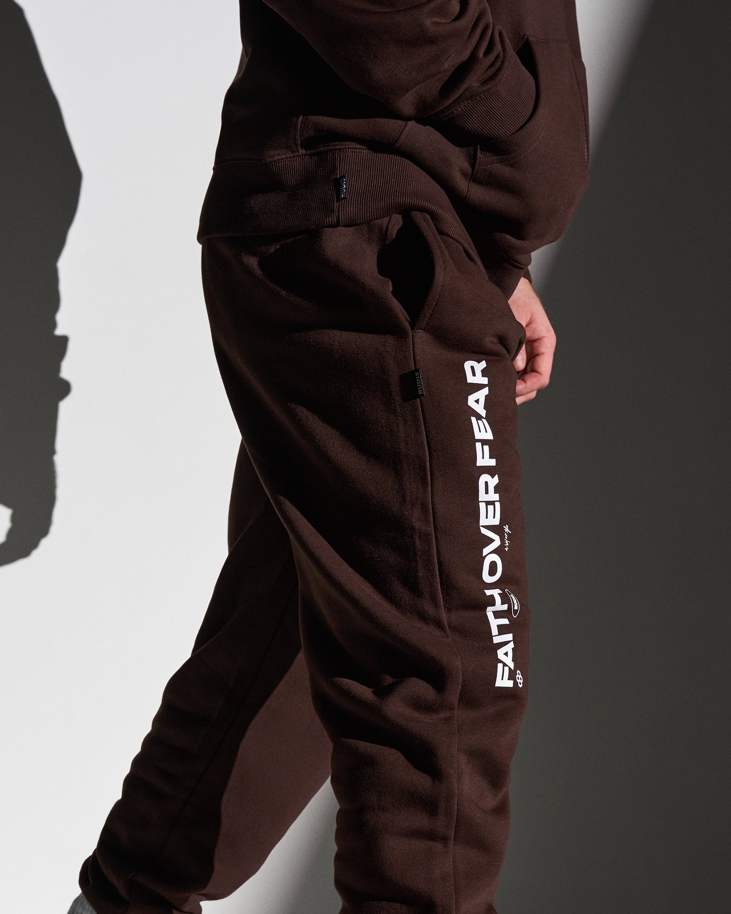 Brown sweatpants with 'Faith Over Fear' text on a plain background