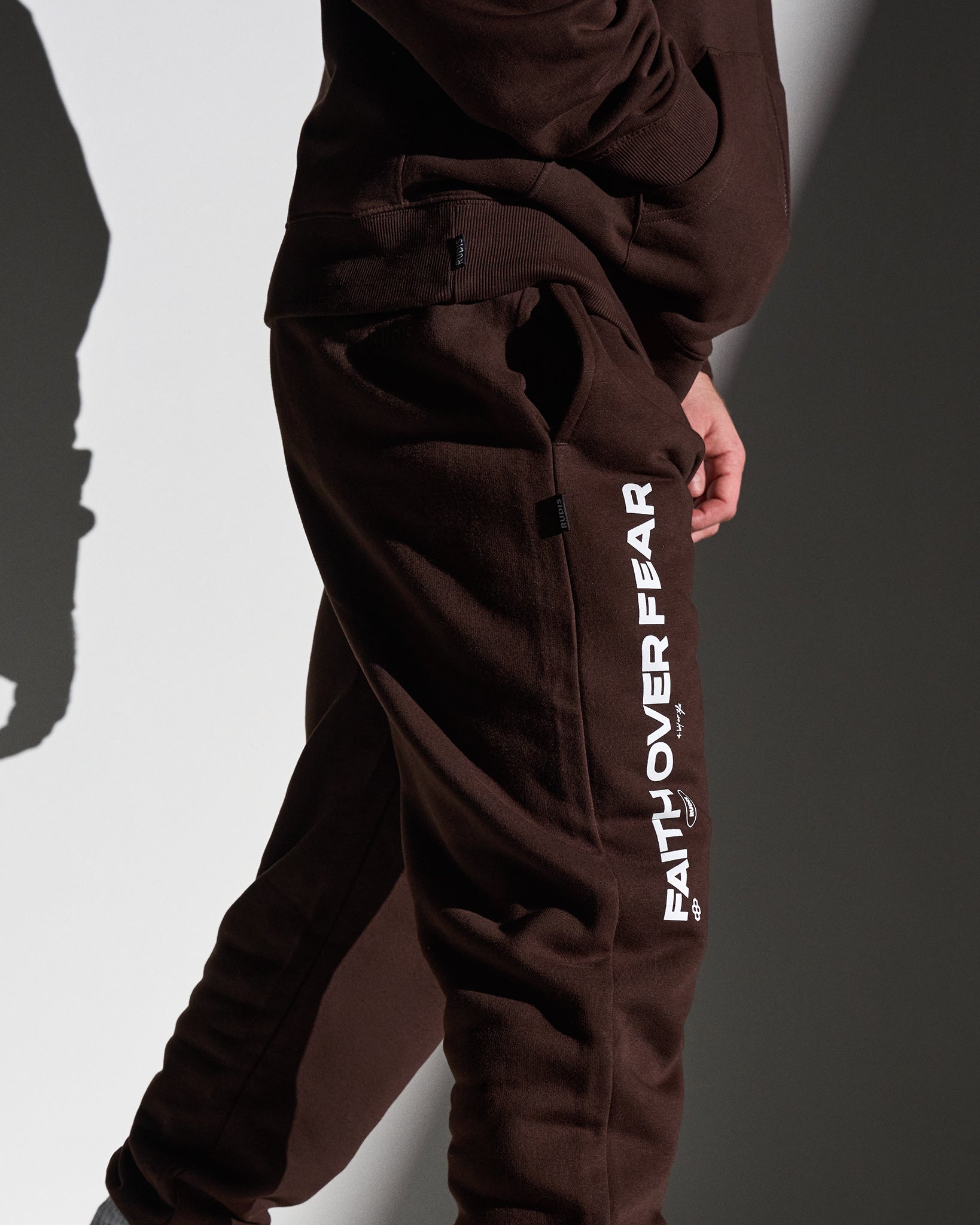 Brown sweatpants with 'Faith Over Fear' text on a plain background