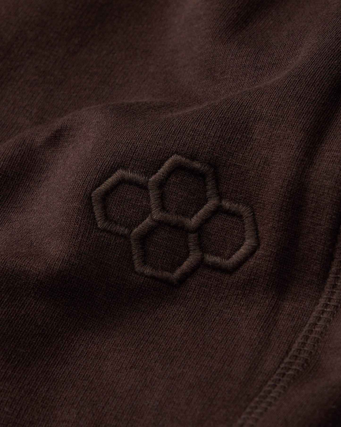 Close-up of a brown fabric with an embroidered Quadhex pattern.