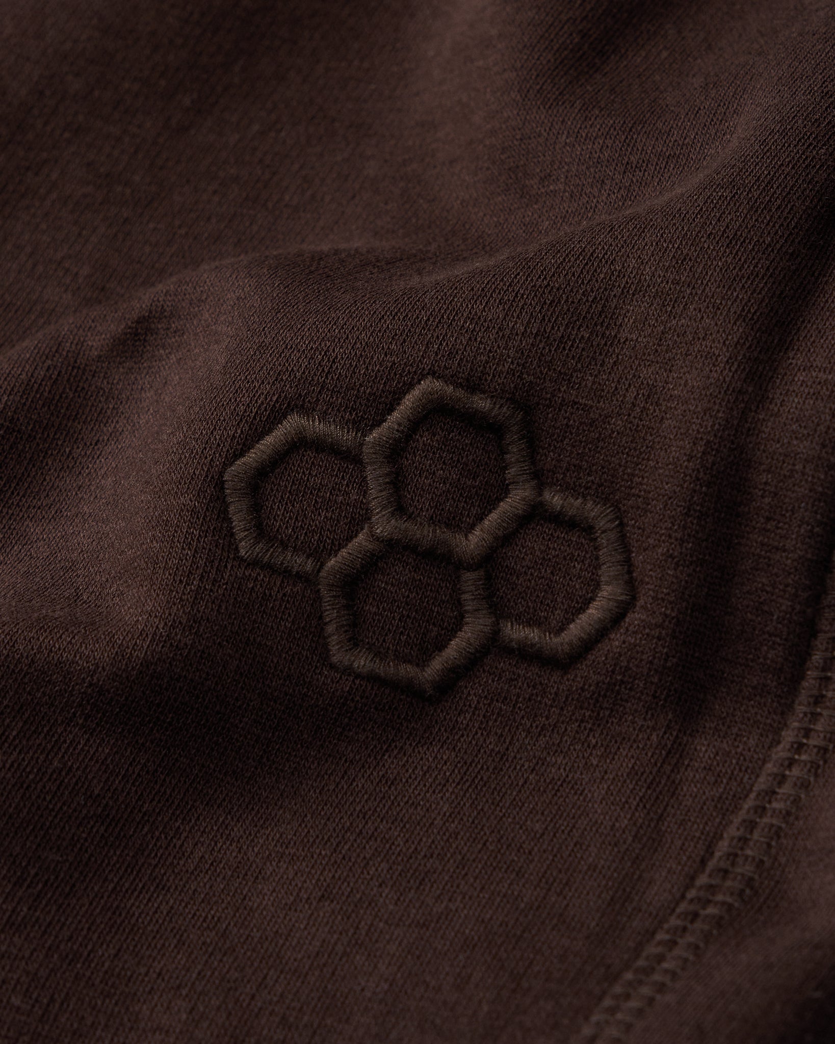 Close-up of a brown fabric with an embroidered Quadhex pattern.