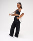 Female model styling RUDIS Comfort Fleece Wide Leg Sweatpants in Black with a sports bra and draped sweatshirt, showing the relaxed silhouette and wide-leg fit. Copy Alt Text
