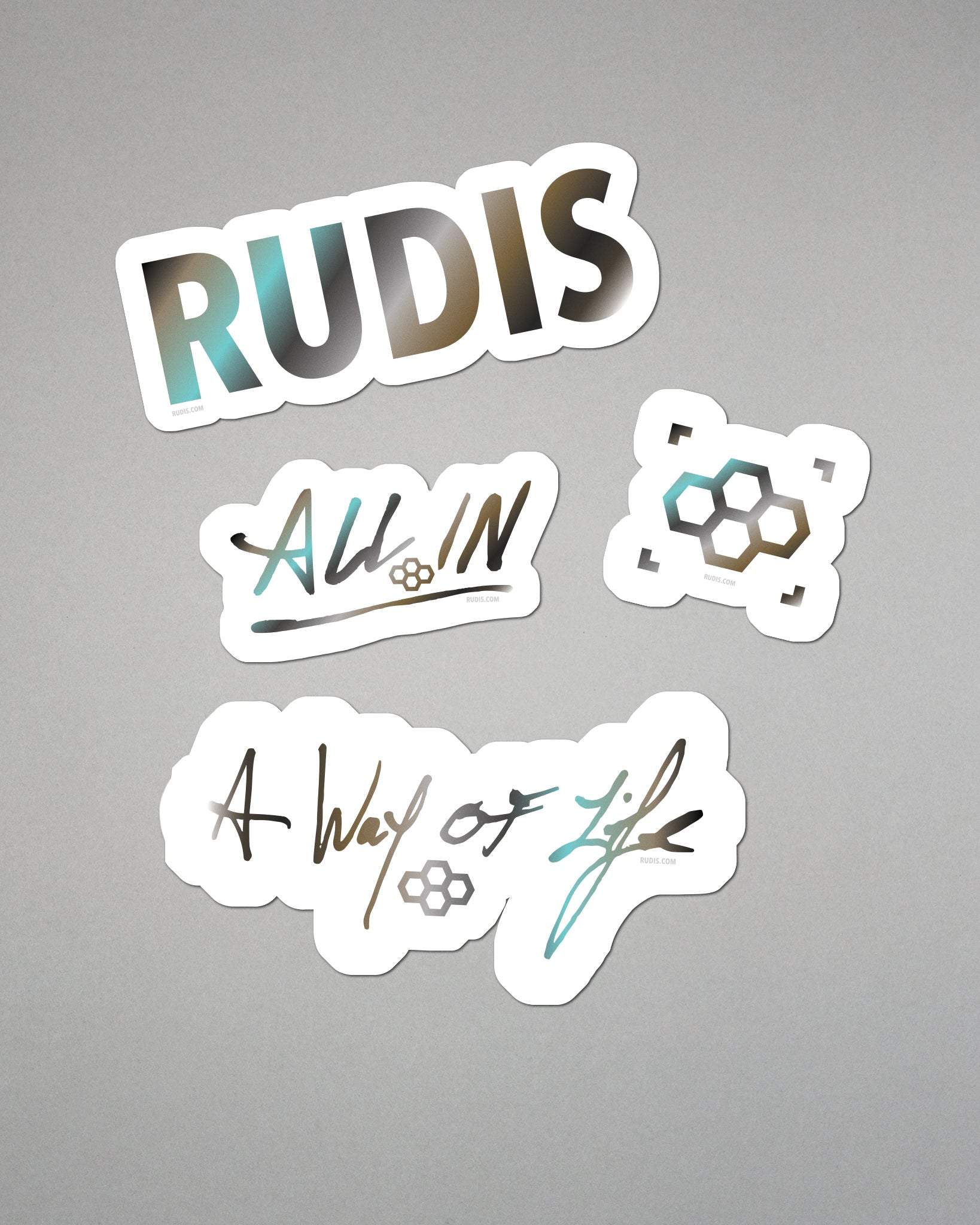 Four stickers with 'RUDIS', 'All In', and 'A Way of Life' text on a gray background