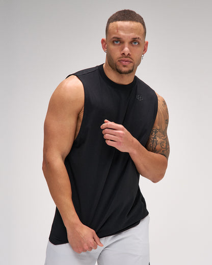 Man wearing a black sleeveless shirt against a gray background