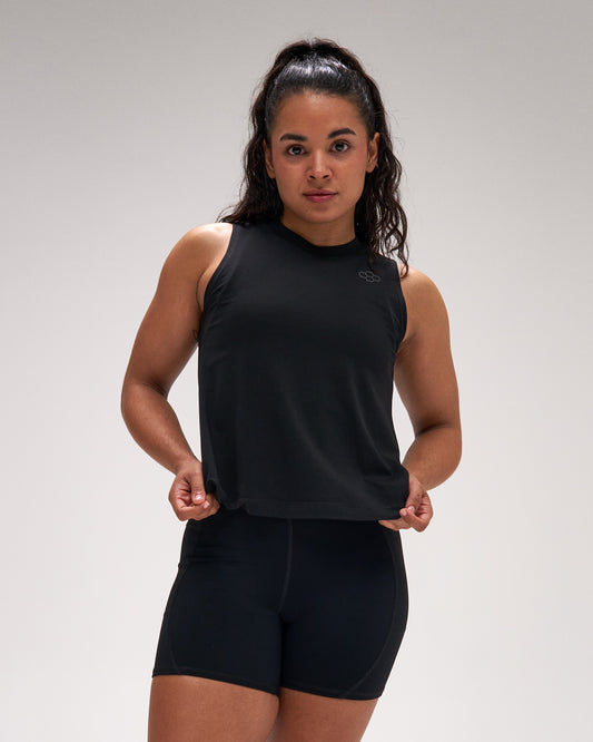 Woman wearing a black sleeveless top and shorts on a gray background