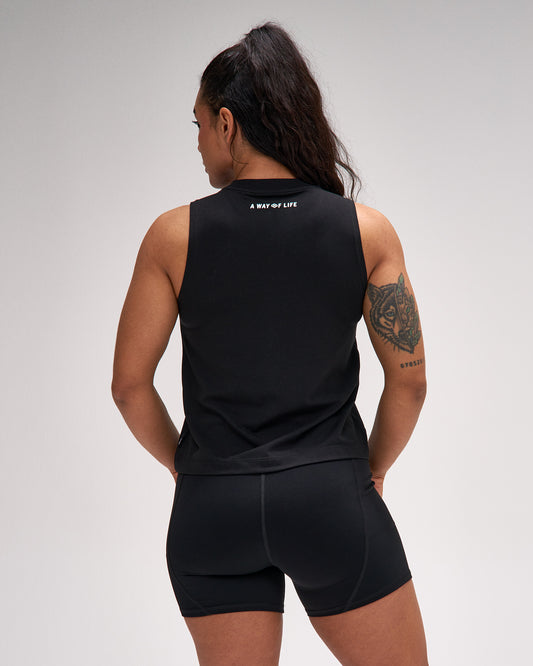 Person wearing a black sleeveless top and shorts set on a gray background