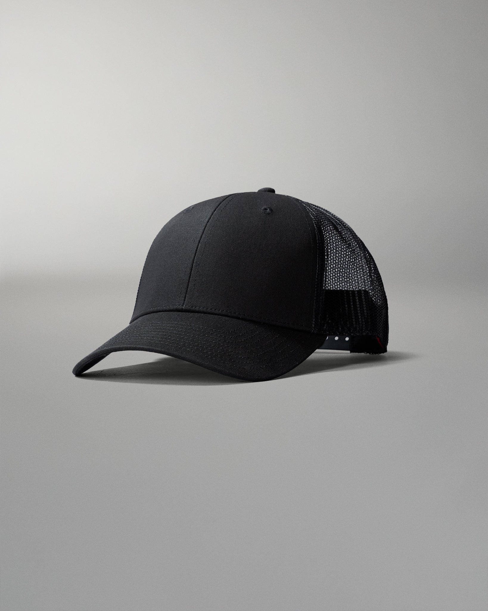 Black cap with mesh back on a gray background