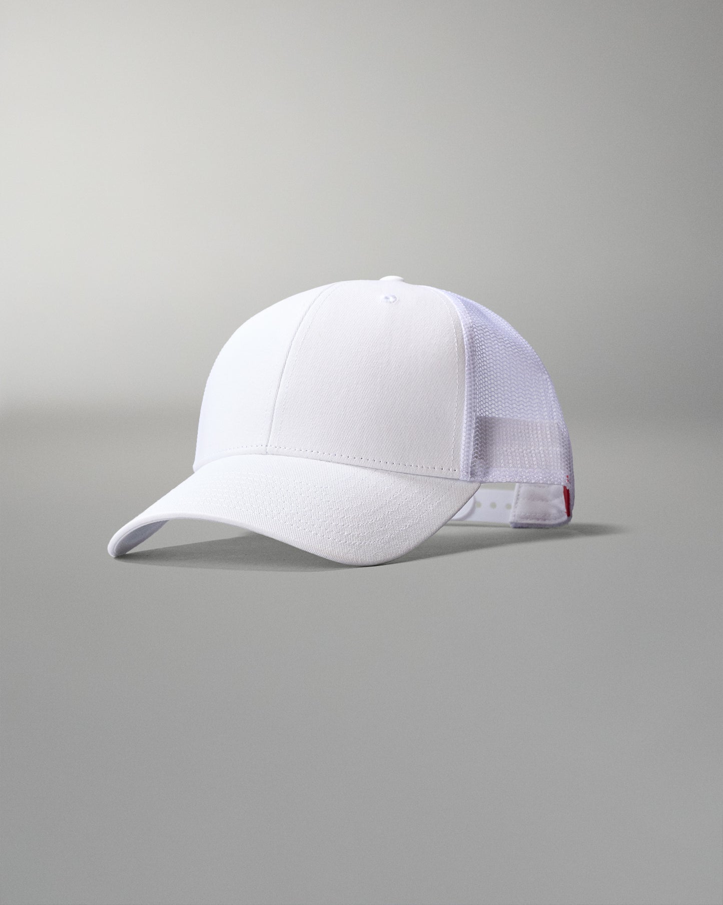 White cap with mesh back on a gray background