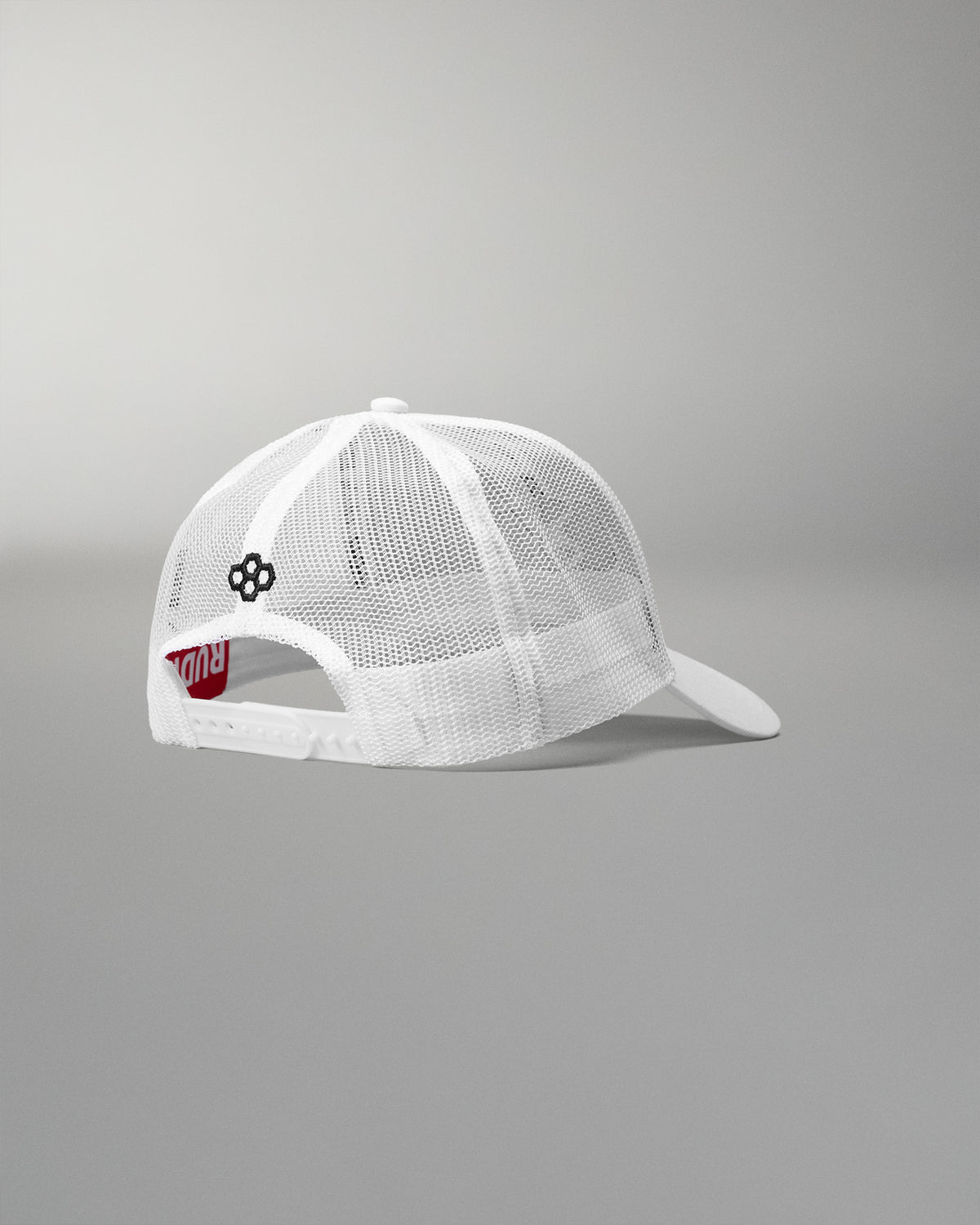 Rear angled view of the RUDIS Fearless Faith Bridge Trucker Hat in White, showcasing breathable mesh panels, adjustable snapback closure and black embroidered RUDIS emblem.