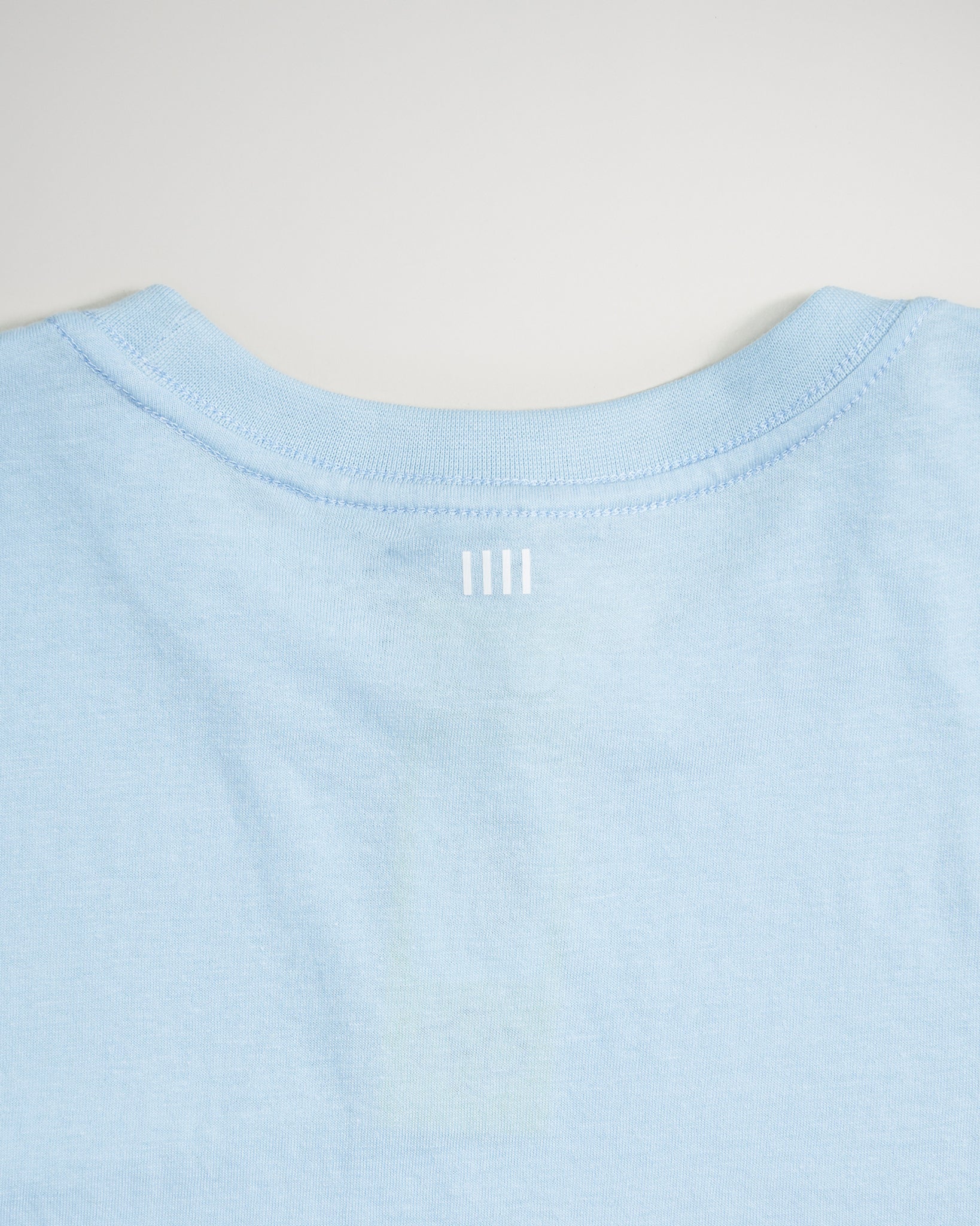 A light blue T-shirt featuring a simple modern design with a subtle white graphic at the neckline