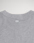 The back view of a gray T-shirt featuring a rounded neckline and three vertical white lines positioned near the collar indicating a simple yet modern design