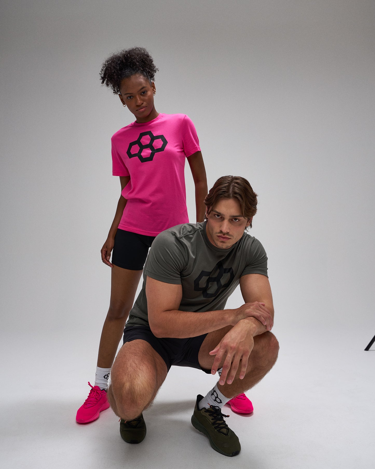 Two people wearing t-shirts with a black logo on a gray background