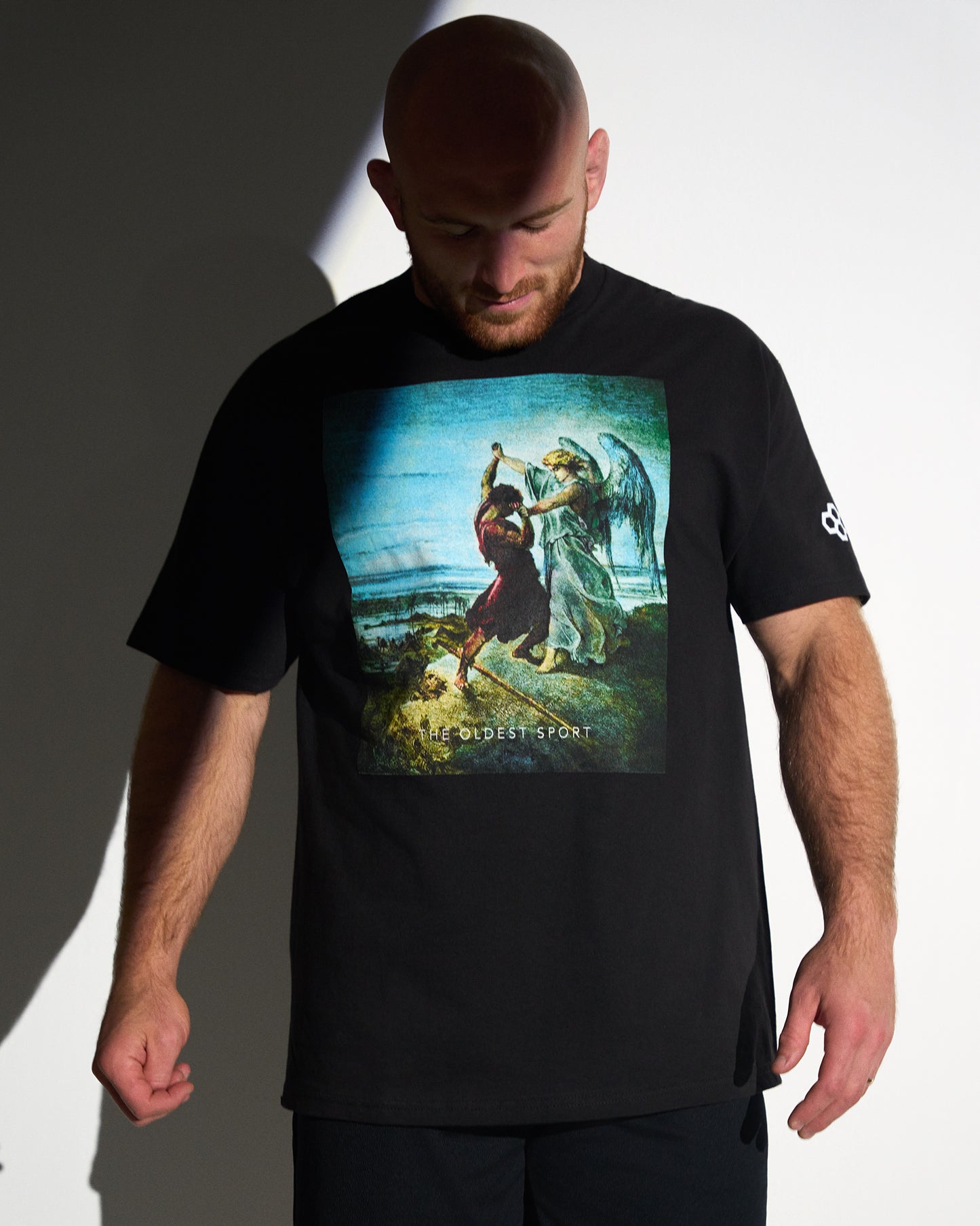Man wearing a black t-shirt with a graphic design on a plain background