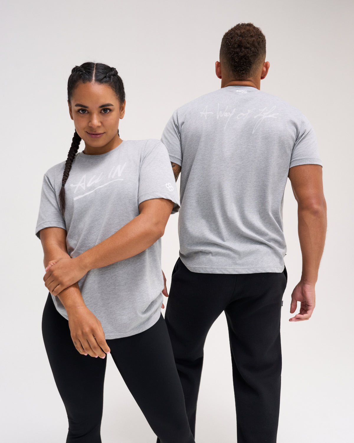 Male and female athletes wearing the gray RUDIS Motto Scripted Elite Super Soft T-Shirt with All In and A Way of Life graphics.