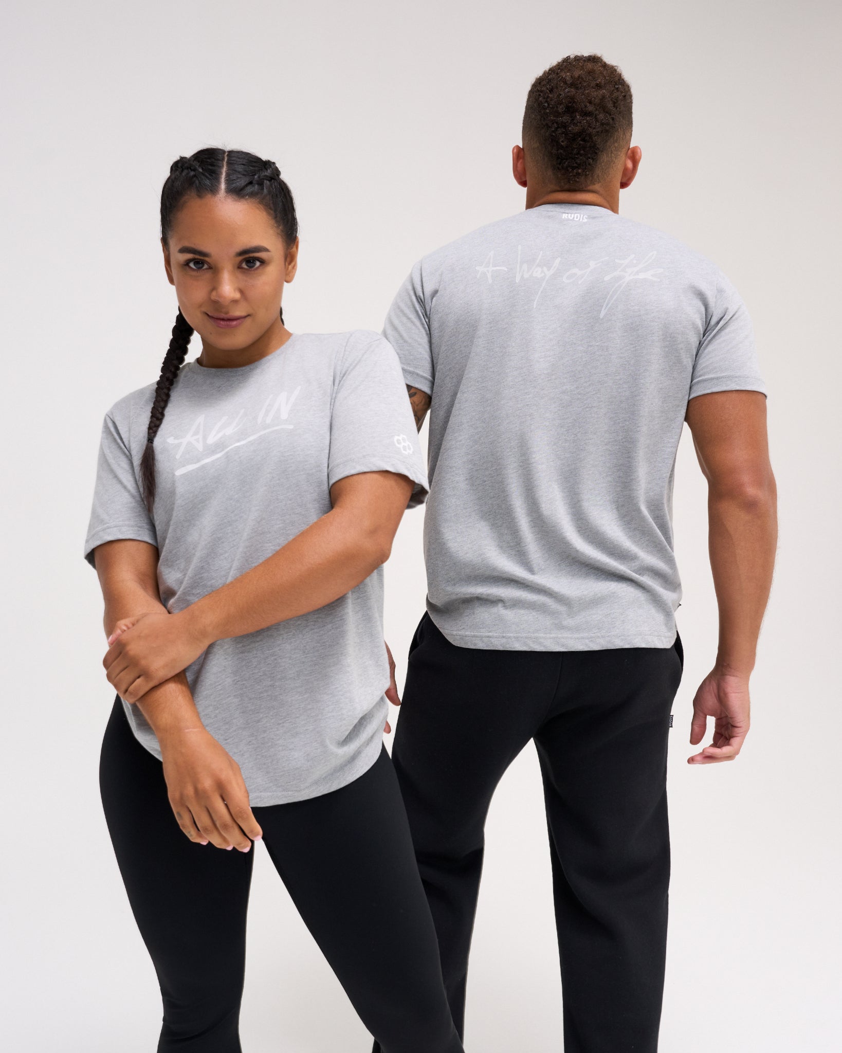 Male and female athletes wearing the gray RUDIS Motto Scripted Elite Super Soft T-Shirt with All In and A Way of Life graphics.
