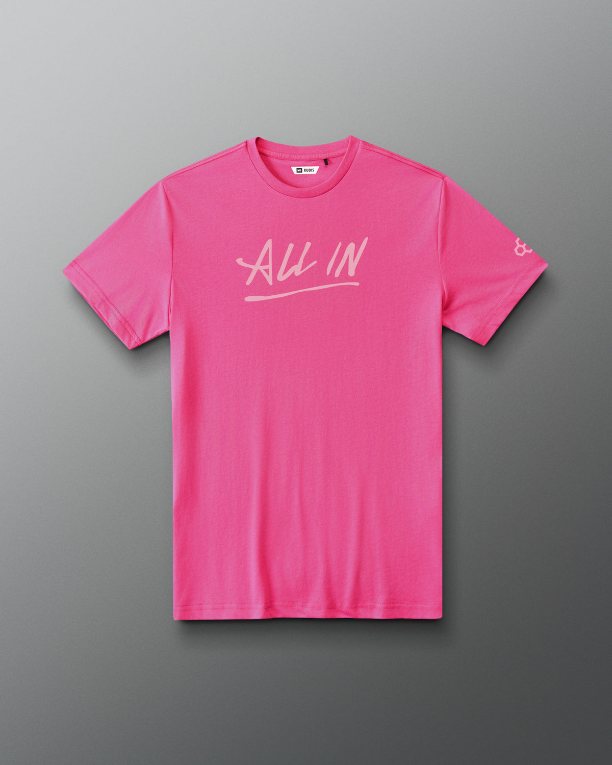 A bright pink short-sleeve t-shirt with 'All In' printed in white script across the chest, displayed flat against a dark gray gradient background.
