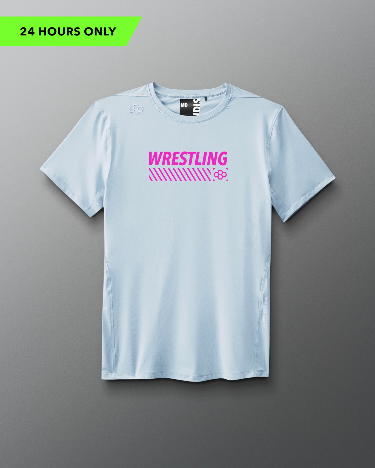 A light blue short-sleeve athletic T-shirt is displayed against a neutral gray background. Bold pink text reading “WRESTLING” is centered on the chest above angled stripes and a small pink RUDIS hex logo. The shirt has an athletic cut with minimal seams and a modern fit.