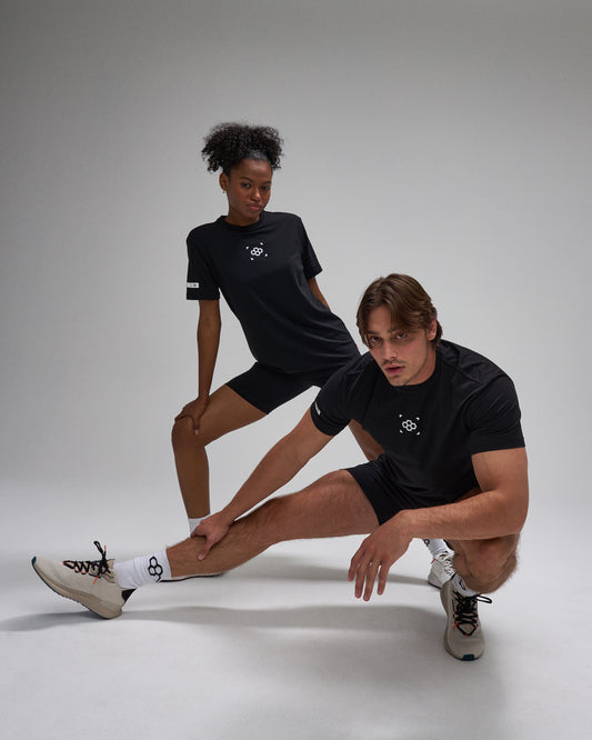 Two people wearing black athletic outfits with a logo on a white background