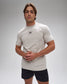 Man wearing a light gray t-shirt with a logo on a gray background