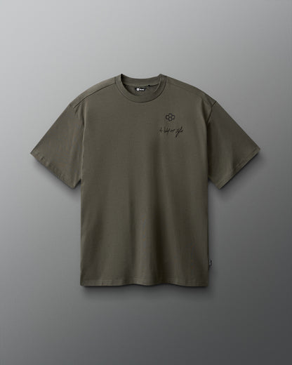 Green t-shirt with a small logo on a gray background