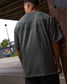 Person wearing a green shirt with text on the back, standing outdoors.
