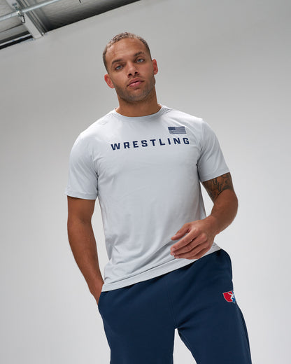 Man wearing a gray 'Wrestling' t-shirt and navy pants on a plain background