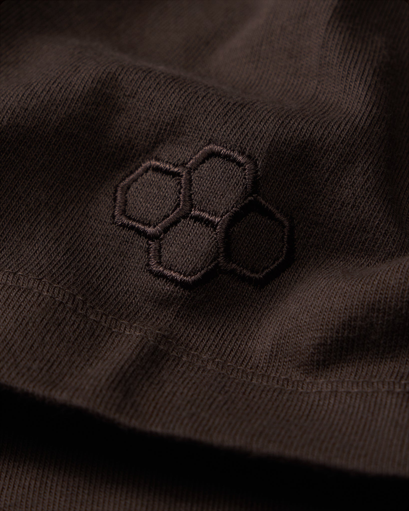 Close-up of a black embroidered design on a dark fabric surface