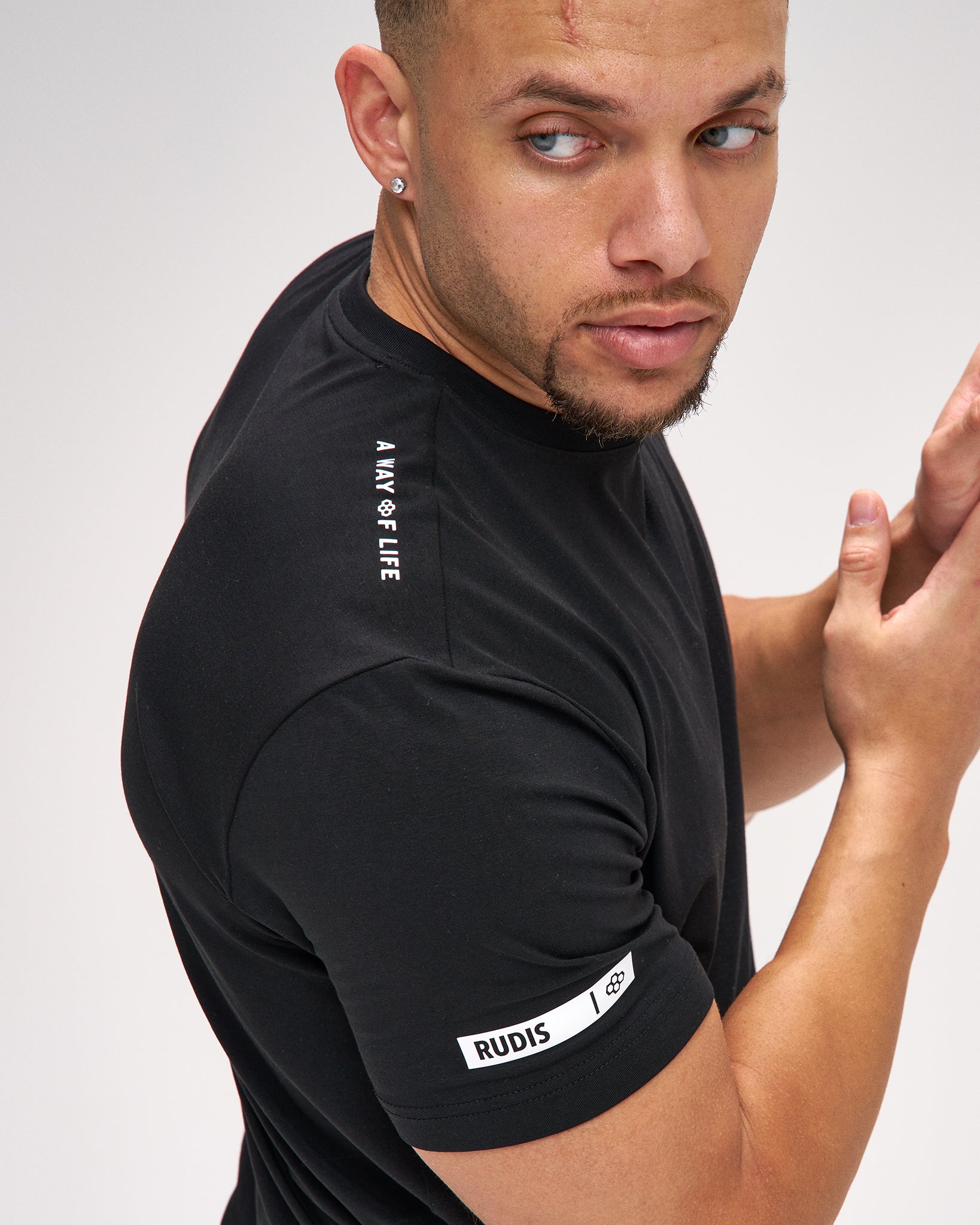 Man wearing a black athletic shirt with visible branding on a plain background