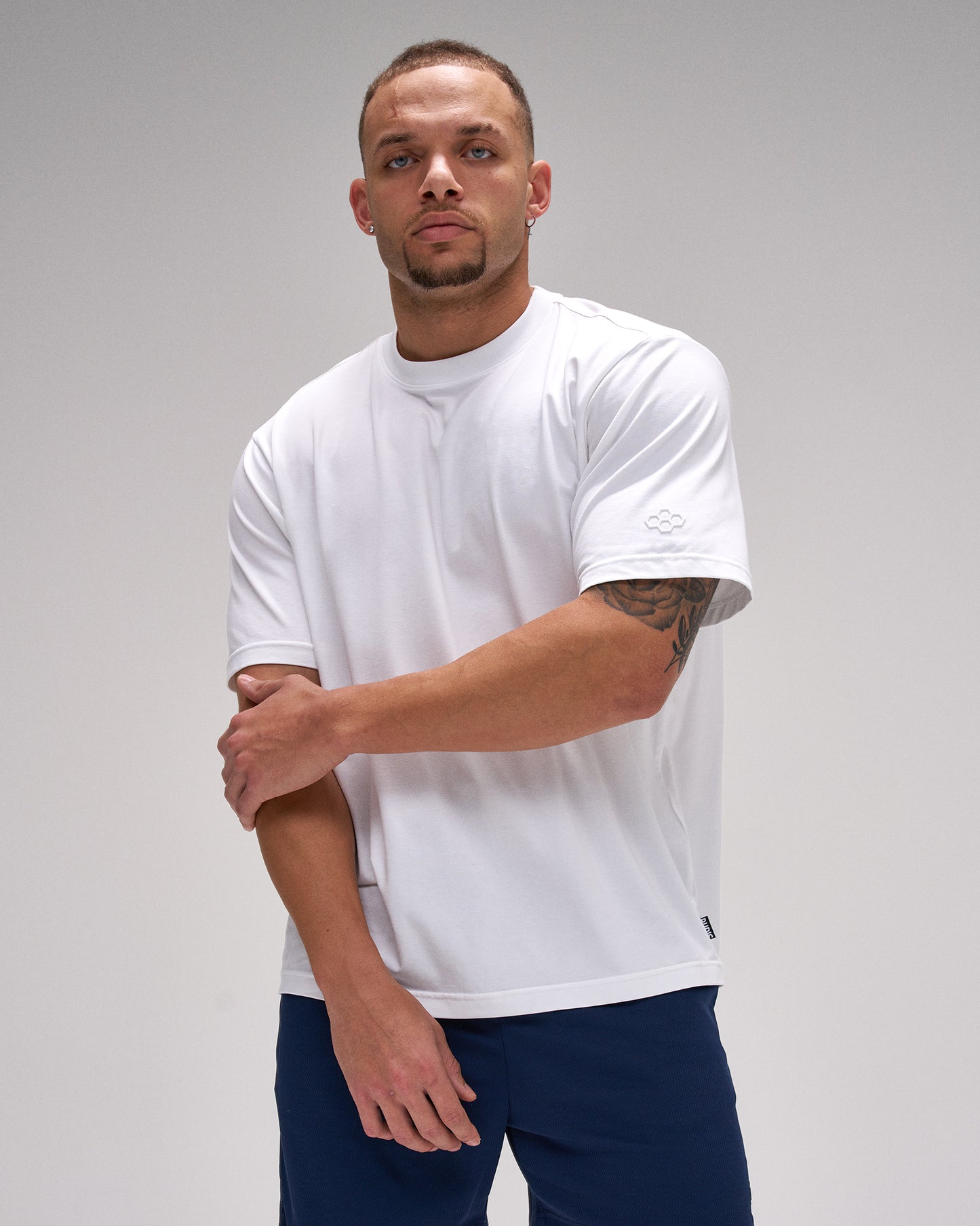 Man wearing a white t-shirt and navy pants against a gray background