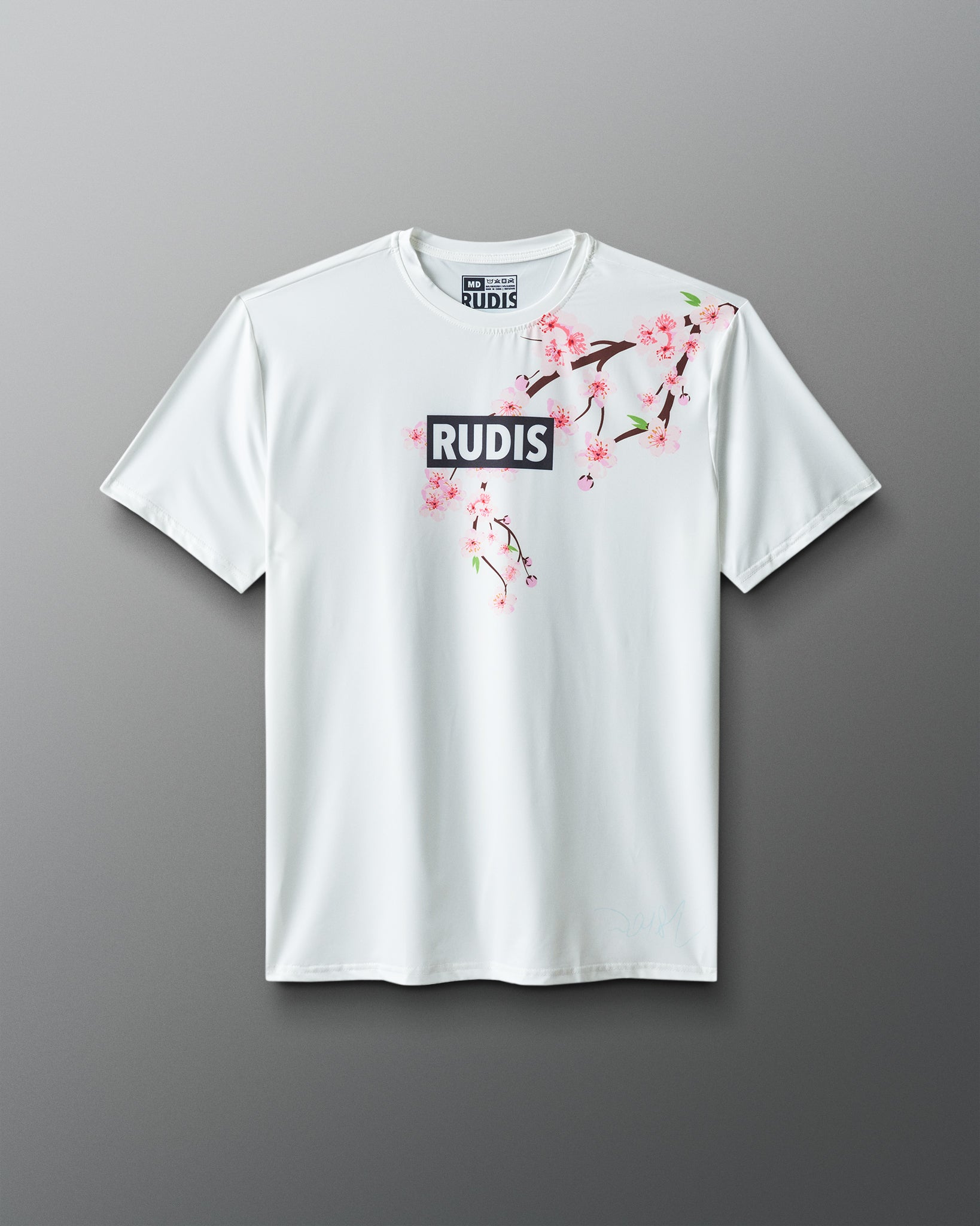 White t-shirt with floral design and 'RUDIS' branding on a gray background