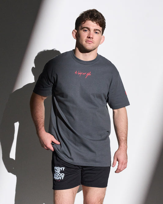 Man wearing a gray t-shirt with red 'A way of life' text and black shorts with white text on a white background