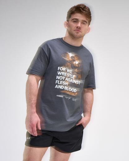 Man wearing a gray t-shirt with a graphic and 'For We Wrestle not against flesh and blood' text on a plain background