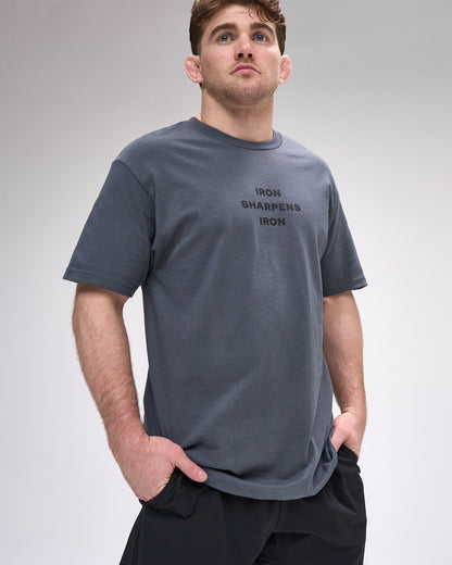 Man wearing a gray t-shirt with 'Iron Sharpens Iron' text on a plain background