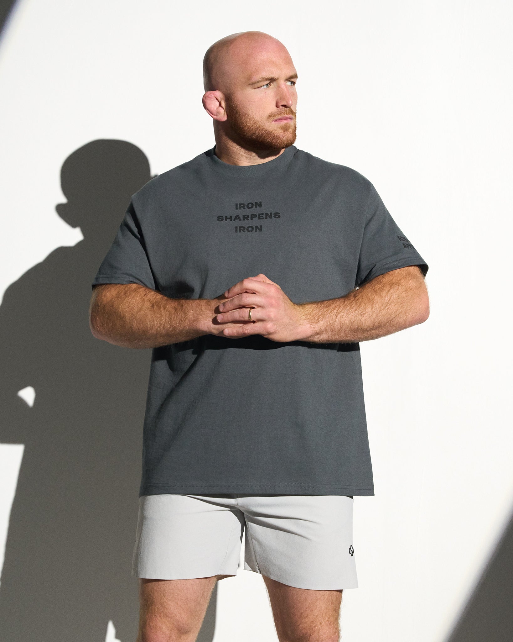 Man wearing a gray t-shirt with text and light gray shorts against a white background