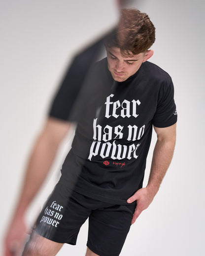 Person wearing a black t-shirt with 'fear has no power' text on a plain background