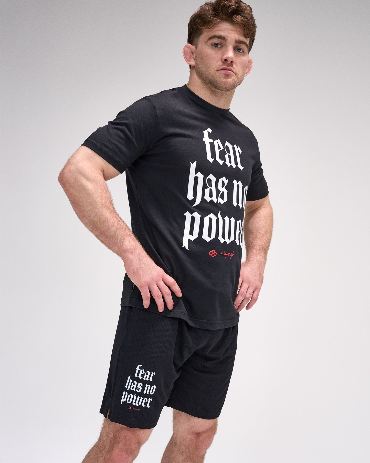 Man wearing a black t-shirt and shorts with 'fear has no power' text on a gray background